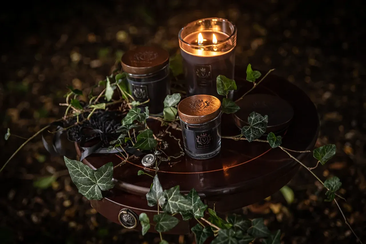 Endless Night-kaarsen uit Grand Collection in verschillende formaten, met houten deksels, in een setting met klimop